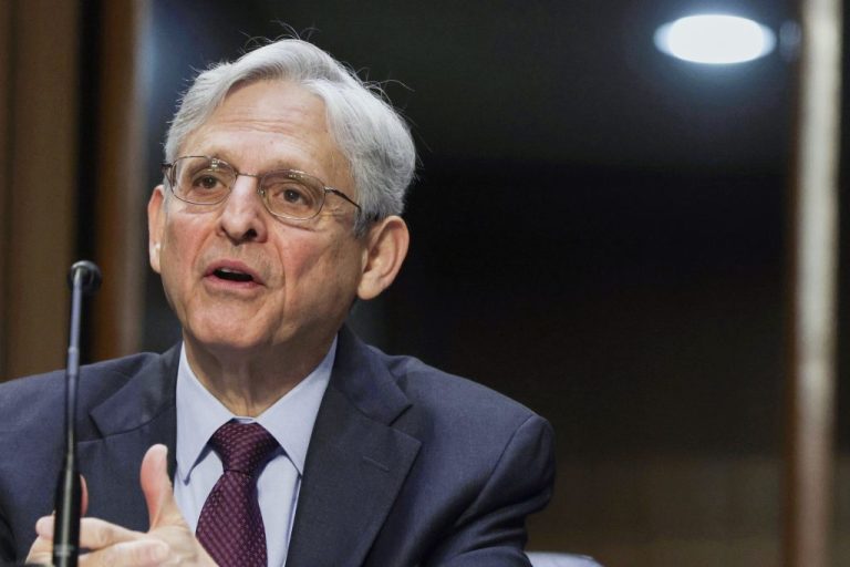 Attorney General Merrick Garland speaks into a microphone.