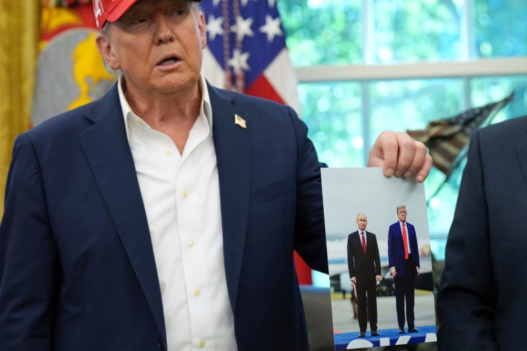 President Donald Trump holds a photo of him and Russian President Vladimir Putin.