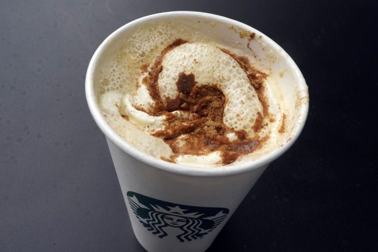 A Pumpkin Spice Latte drink rests on a table.