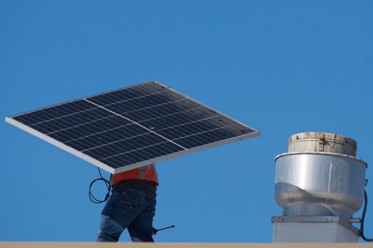 A worker carries a solar panel on the roof of the Alta Sea building, an urban, ocean-based research and blue technology innovation campus, at Berth 58 in the Port of Los Angeles on Sept. 4, 2025. (AP Photo/Damian Dovarganes)