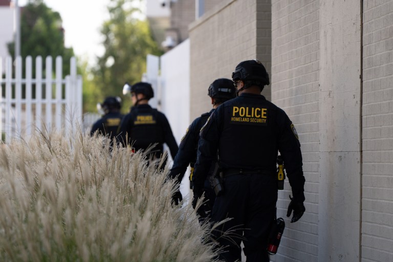 Department of Homeland Security officials walk to the gates of an Immigration and Customs Enforcement facility.