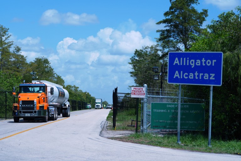 A truck drives by Alligator Alcatraz.