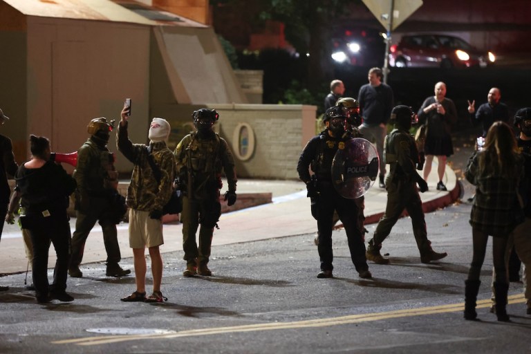 People protest outside a U.S. Immigration and Customs Enforcement facility as federal agents walk into the street, in Portland, Oregon, Wednesday, Oct. 1, 2025. (AP Photo/Amanda Loman)