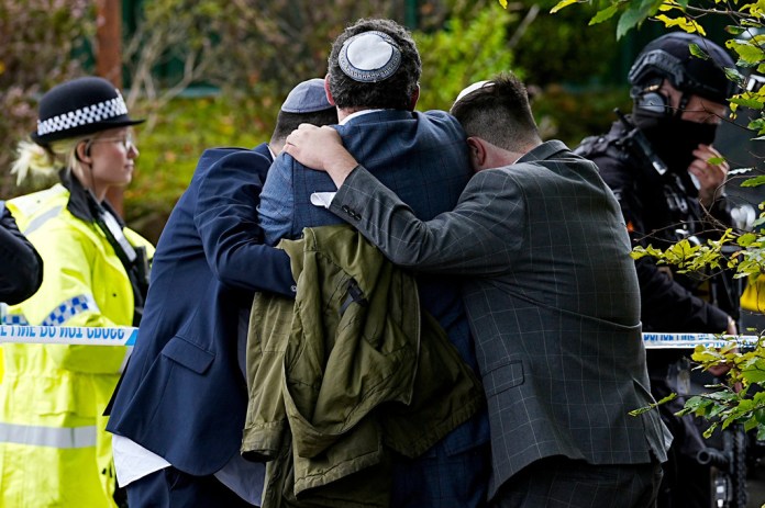 Members of the Jewish community comfort each other near to the Heaton Park Hebrew Congregation synagogue, in Crumpsall, Manchester, England, Thursday, Oct. 2, 2025 after Police reported that two people were killed and three others were seriously injured in a synagogue attack in northern England. 
