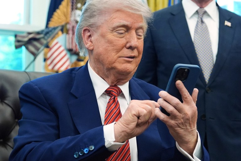 President Donald Trump looks at an iPhone.