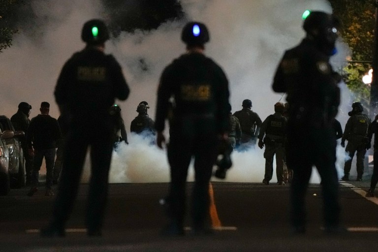 Officers stand near tear gas outside ICE facility in Portland, Oregon.