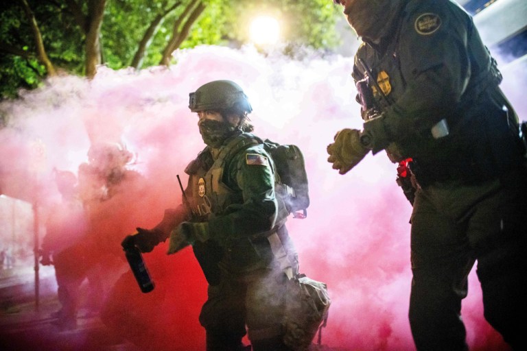 Police and federal officers throw gas canisters to disperse protesters near a U.S. Immigration and Customs Enforcement facility in Portland, Ore. on Sunday, Oct. 5, 2025.