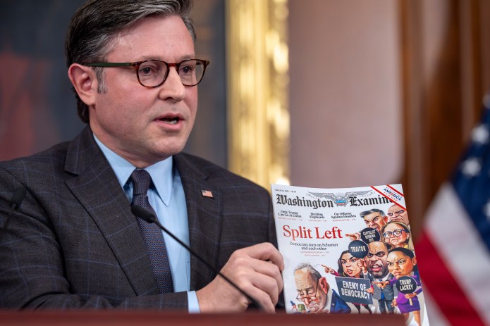 Speaker of the House Mike Johnson, R-La., holds up a news article depicting congressional Democrats during a news conference.