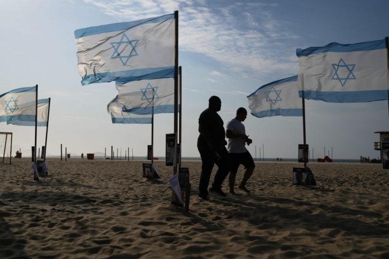 Activists walk through Israeli flags and photos of Israeli hostages held by Hamas in the Gaza Strip