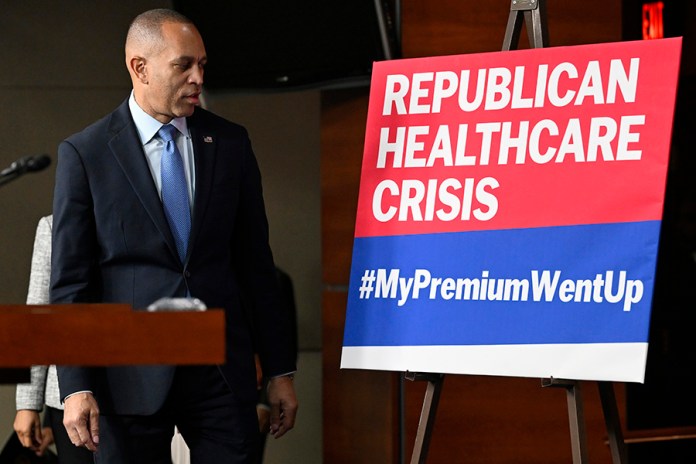 House Minority Leader Hakeem Jeffries, D-N.Y., passes a sign on a stage that the House Democratic leaders held a news conference on the 8th day of government shutdown at the U.S. Capitol on Wednesday, Oct. 8, 2025, in Washington. (AP Photo/John McDonnell)