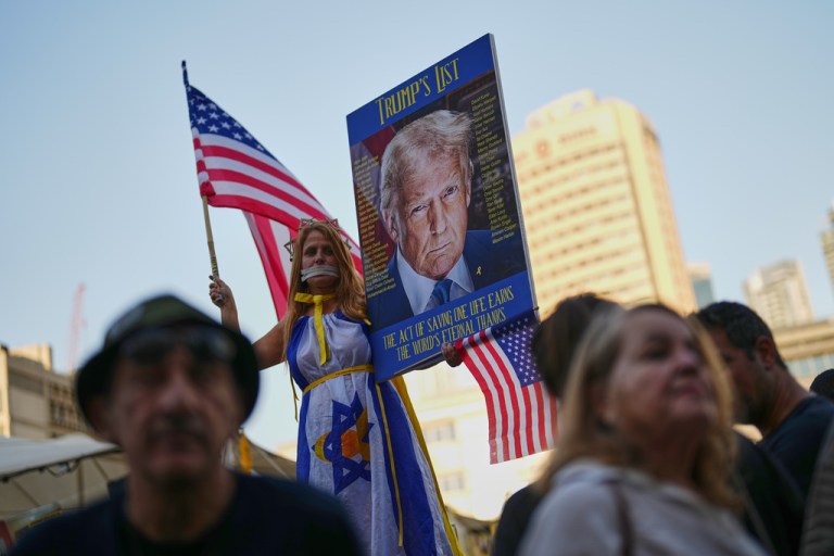 Holding up a sign with an image depicting the U.S. President Donald Trump a woman takes part in a rally in support of hostages kidnapped by Hamas at a plaza known as hostages square, in Tel Aviv, Israel, Saturday, Oct. 11, 2025, ahead of the expected release of the hostages held in the Gaza Strip. (AP Photo/Francisco Seco)