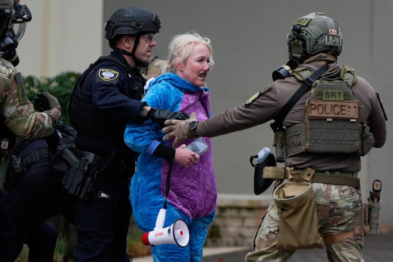 A demonstrator is detained outside a U.S. Immigration and Customs Enforcement facility during a protest on Saturday, Oct. 11, 2025, in Portland, Ore. (AP Photo/Jenny Kane)