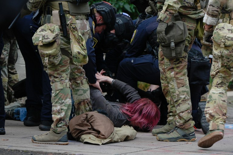 A demonstrator is detained outside an Immigration and Customs Enforcement facility.