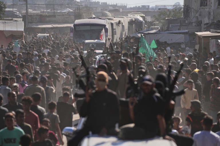 Hamas gunmen carry freed Palestinian prisoners in escort buses.