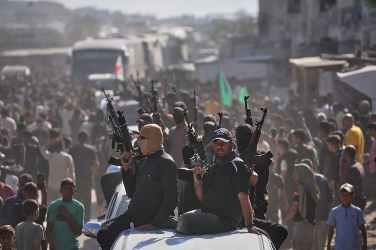 Hamas gunmen on pickup trucks escort buses carrying freed Palestinian prisoners.