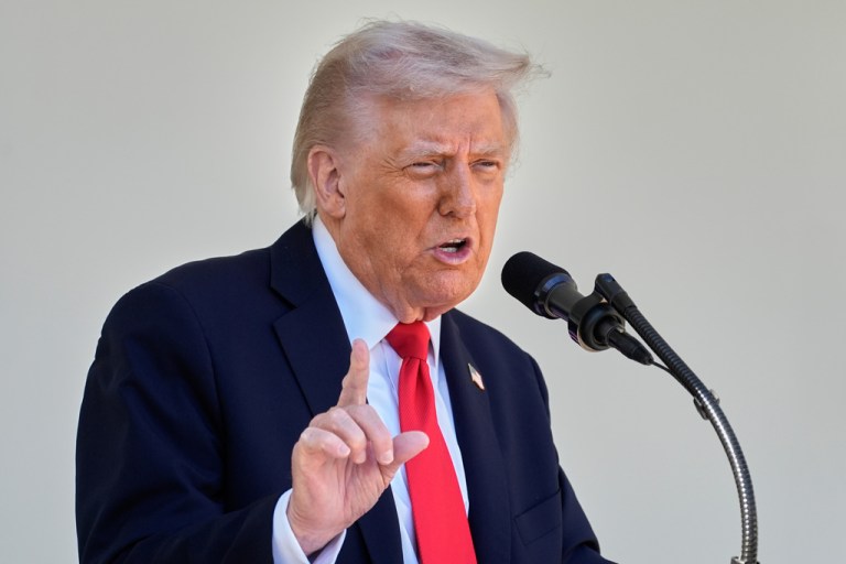 President Donald Trump speaks into a microphone.