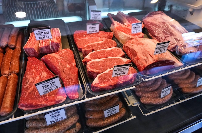 A selection of beef cuts and sausages are displayed.