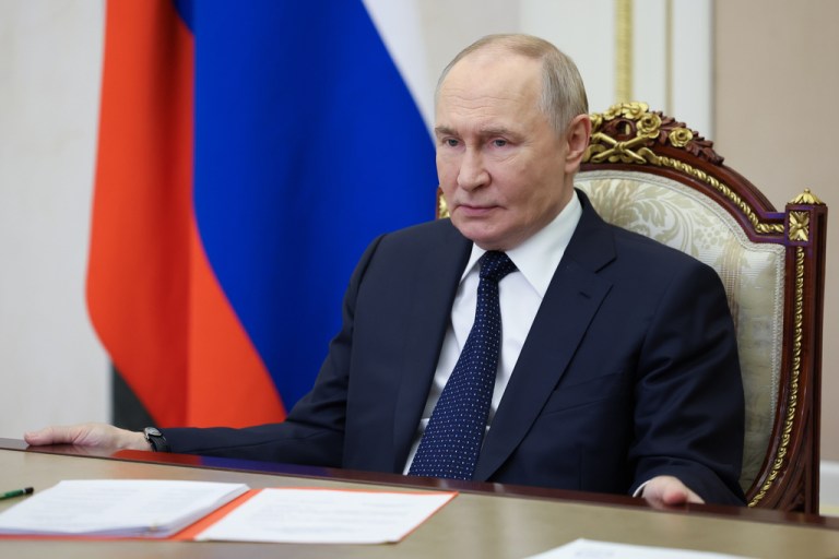Russian President Vladimir Putin sits at a desk.