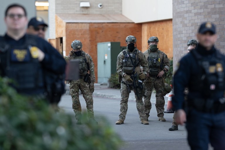 Law enforcement officers watch from a United States Immigration and Customs Enforcement facility.