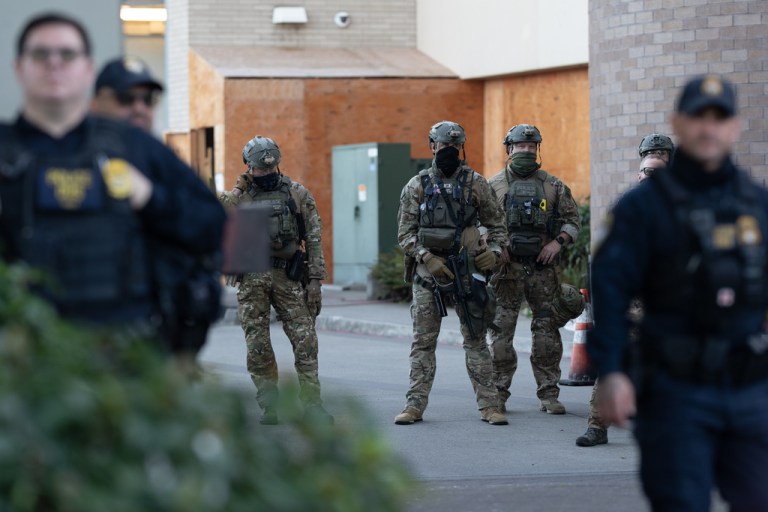 Law enforcement officers watch from a United States Immigration and Customs Enforcement facility.