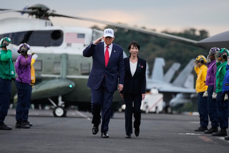 Donald Trump walks on a tarmac with Japanese Prime Minister Sanae Takaichi