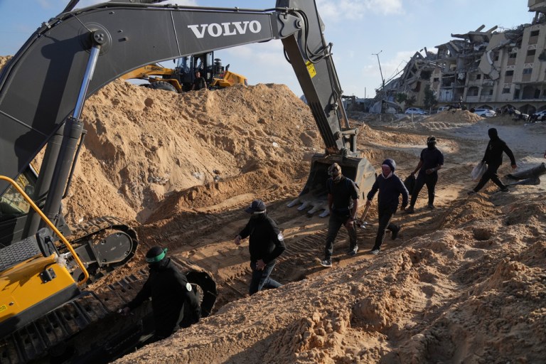Members of the al-Qassam Brigades, the military wing of Hamas, and Egyptian workers search for the bodies of hostages in a tunnel.