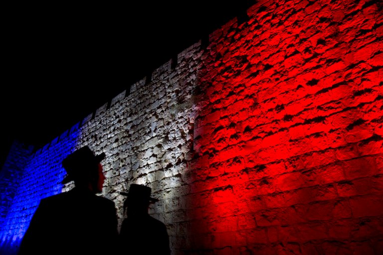 In this Sunday, Nov. 15, 2015 file photo, two Ultra-Orthodox Jews look at Jerusalem's Old City walls illuminated by the colors of the French national flag in solidarity with France after attacks in Paris, in Jerusalem.