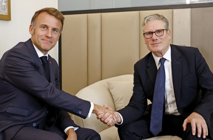 Two spectators share a handshake at the history-making summit in Sharm el Sheikh, Oct. 13, 2025. (Yoan Valat / AP)