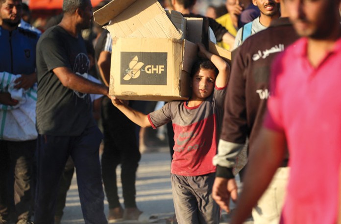 A boy carrying aid walks near the Nusseirat refugee camp in the central Gaza Strip, used by food-seeking Palestinians to reach an aid distribution point set up by the Gaza Humanitarian Foundation on June 25, 2025. (EYAD BABA/AFP via Getty Images)