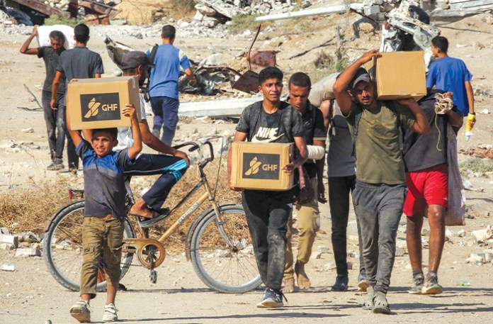 Boys walk with boxes of humanitarian aid they received GHF, on Aug. 22, 2025. (EYAD BABA/AFP via Getty Images)