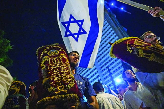 Worshipers holding torahs dance and celebrate during the 'hakafot' ritual of Simchat Torah on the day four more hostage bodies are released, and the day after 20 living hostages were released, in hostage square on October 14, 2025 in Tel Aviv, Israel. This week, the 20 living hostages held by Hamas in Gaza were returned to Israel as part of a ceasefire agreement designed to end the war sparked by the attacks of Oct. 7, 2023. But much uncertainty remains about the future of the peace process, and the fate of deceased hostages whose remains are supposed to be returned to Israel. There is speculation that Hamas and its allied groups may not be able to locate the remains of all 28 hostages believed to be held in Gaza. (Photo by Alexi Rosenfeld/Getty Images)