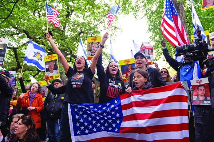 People hold US and Israeli flags during a "Bring them home" rally in support for the release of Israeli hostages held by Hamas in Gaza on October 12, 2025 in New York City. Israel has accepted a truce plan put forward by U.S. President Donald Trump and, on October 10, withdrew its forces from several areas of Gaza. The move set off a 72-hour deadline for the release of hostages held by Hamas, two years after the Palestinian militant group’s October 7, 2023 attack. (Photo by Noam Galai/Getty Images)