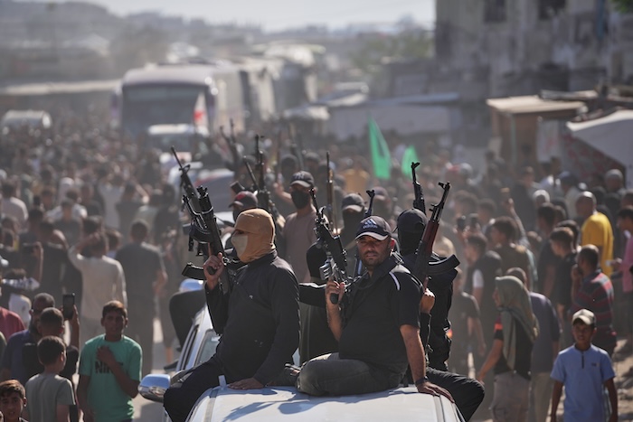 Hamas gunmen on pickup trucks escort buses carrying freed Palestinian prisoners.