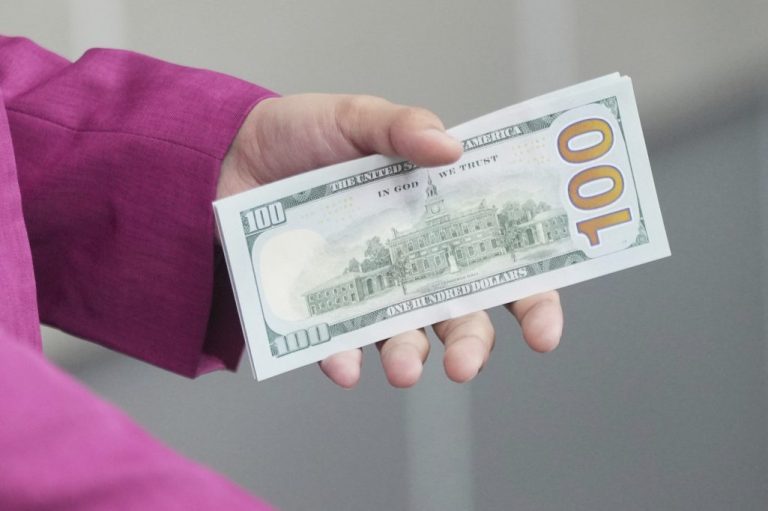 An employee holds U.S. dollar banknotes at a money changer.