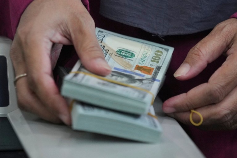 An employee holds U.S. dollar notes at a money changer in Jakarta.