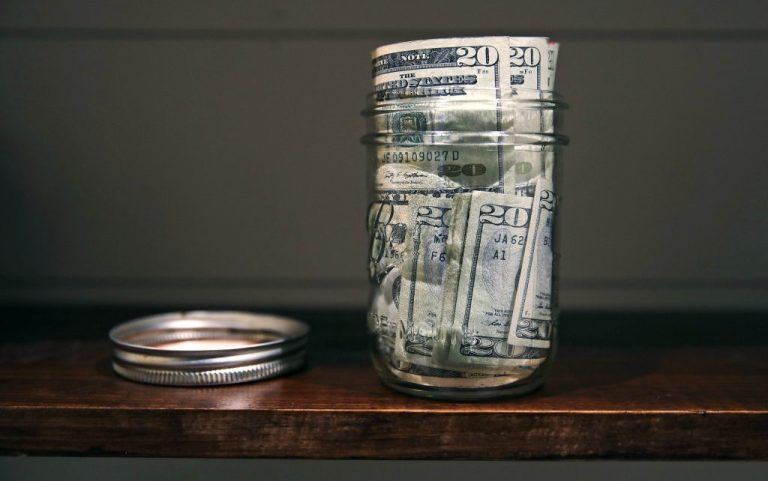 A jar filled with money on a shelf.