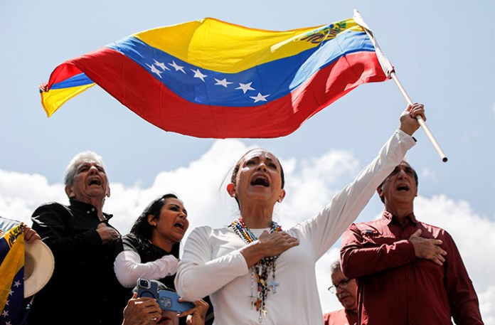 Opposition leader Maria Corina Machado (center) waves a Venezuelan national flag during a rally. (Cristian Hernandez/AP)