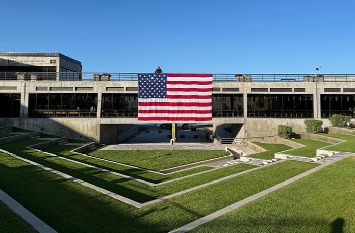 A national flag hangs over the site where conservative activist Charlie Kirk was shot and killed at Utah Valley University last week on Sept. 17, 2025, in Orem, Utah. (Jesse Bedayn/AP)