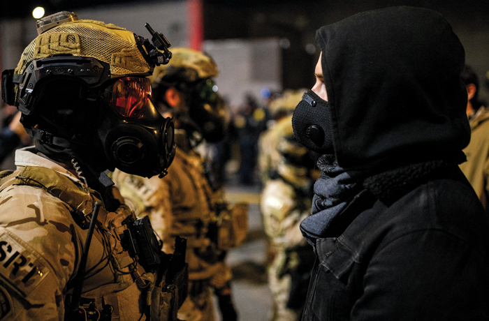 An officer with the Homeland Security Special Response Team stands against a protester outside an Immigration and Customs Enforcement facility in Portland, Oregon on Oct. 6. (Stephen Lam/San Francisco Chronicle via AP)