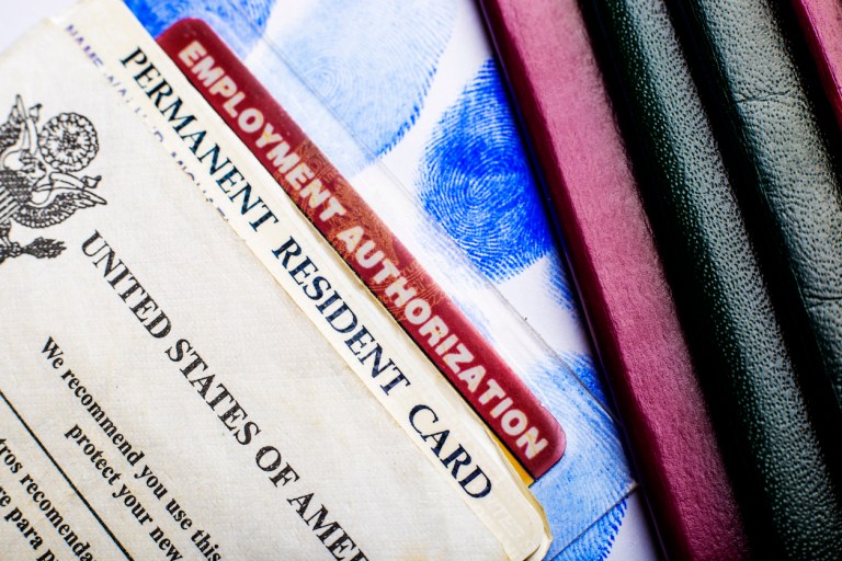 USA permanent resident card (Green Card) with Employment Authorization card next to passports and fingerprints