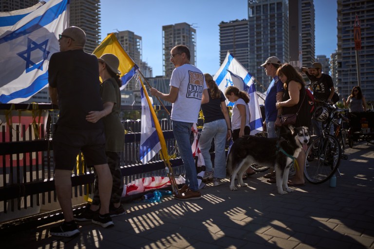 People carrying flags watch for the coffin of a slain hostage