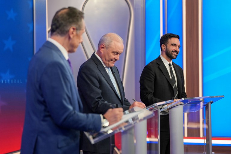 Andrew Cuomo, Curtis Sliwa, and Zohran Mamdani stand at podiums during a mayoral debate
