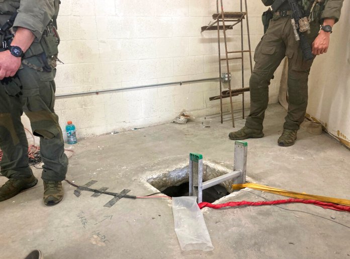 Law enforcement officers stand by the opening of a cross-border tunnel.