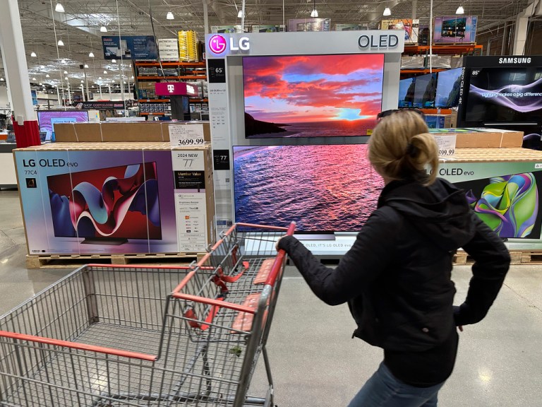 A shopper passes a display of televisions at a Costco warehouse.