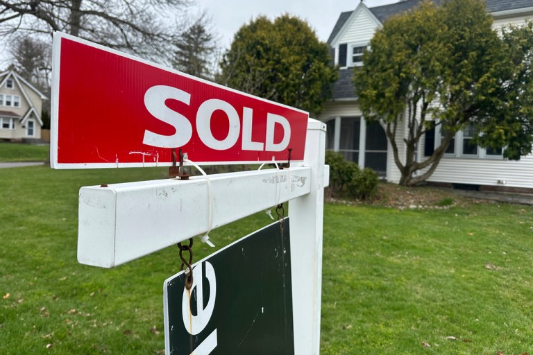 A sold sign hangs in front of a house.