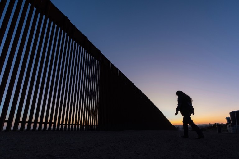 A volunteer walks along a road next to the border wall separating Mexico and the United States.