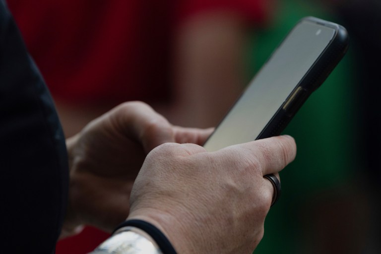 Hands holding a phone in an airport.