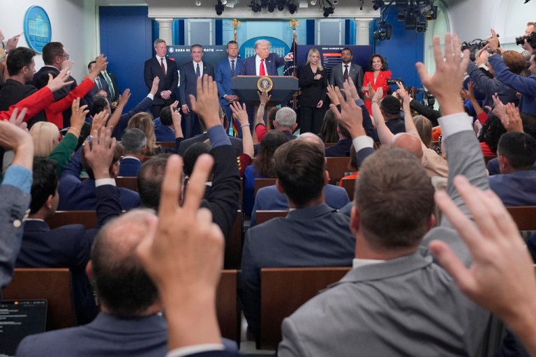 President Donald Trump, center, points to members of the media as he speaks with reporters.