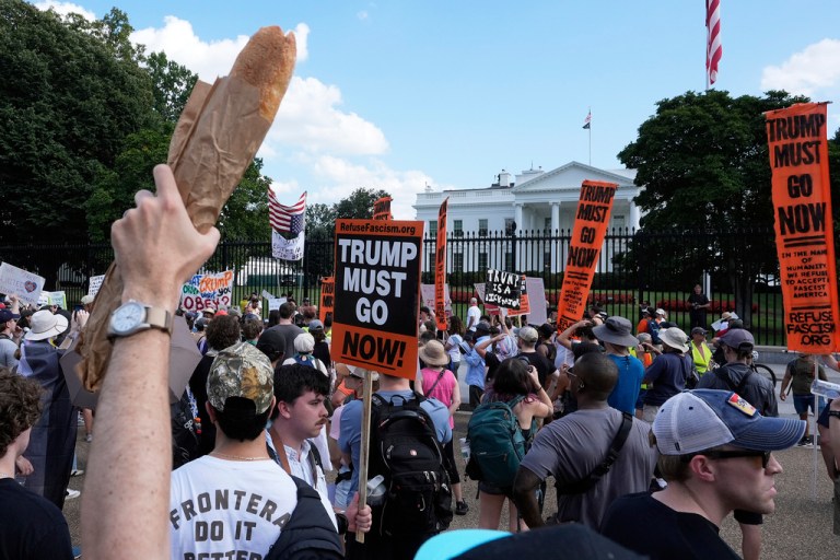 An activist holds up a baguette in support of a fired former Justice Department employee who hurled a sandwich at a federal law-official.