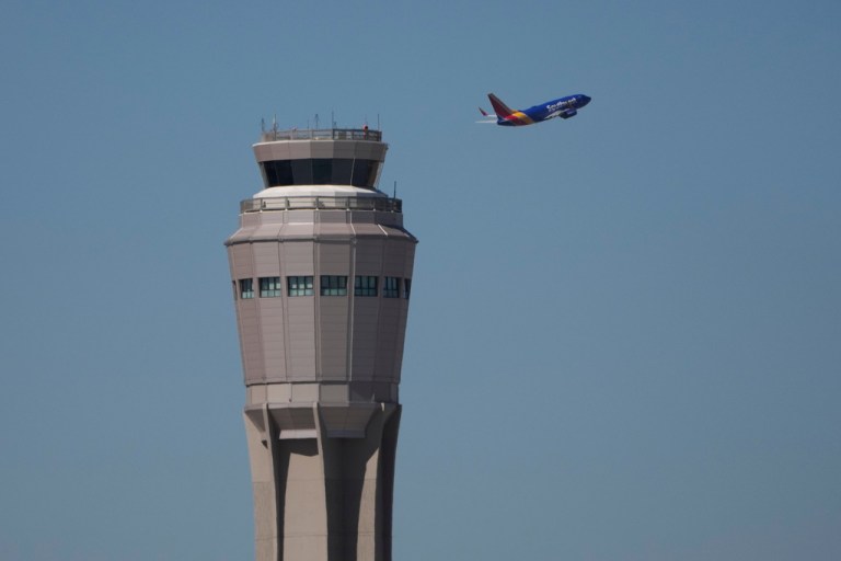 A plane takes off near the air traffic control tower at Harry Reid International Airport, Tuesday, Oct. 7, 2025, in Las Vegas. (AP Photo/John Locher)